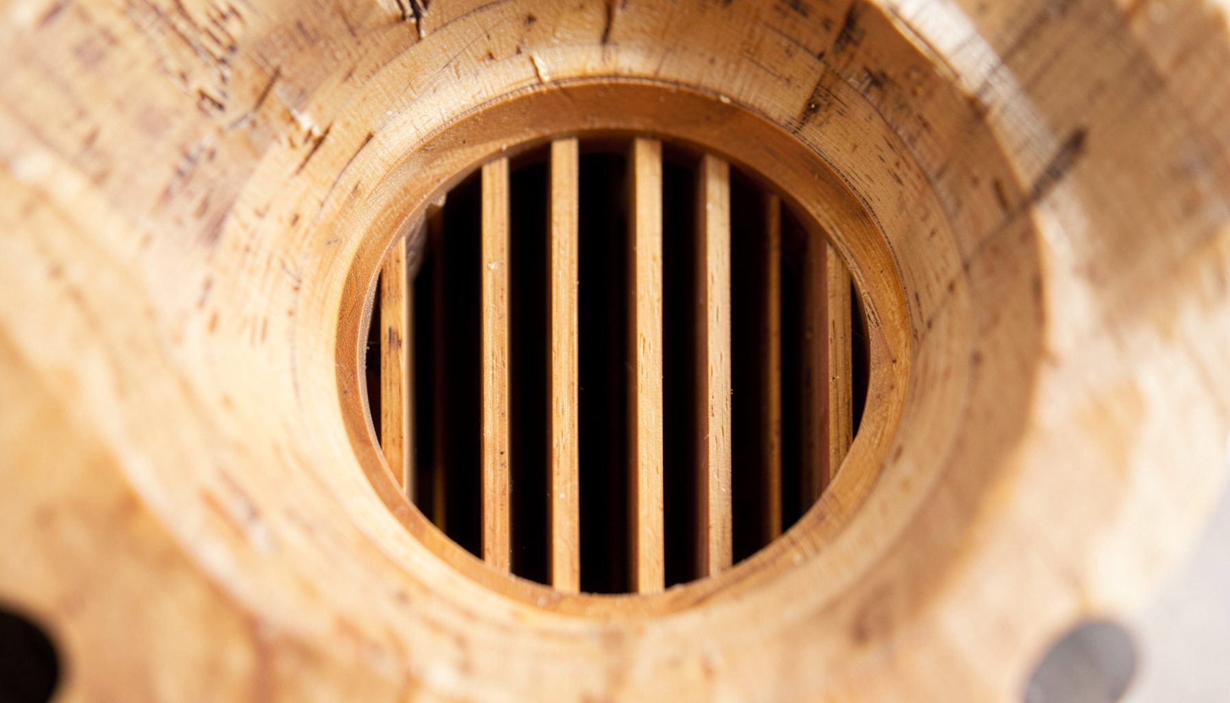 Close-up view into the throat of a bi-radial wood horn, showing the vertical fin array dividing the opening into multiple narrow cells. Warm birch tones contrast with the dark interior cavities, emphasizing the precision of the CNC-machined geometry.